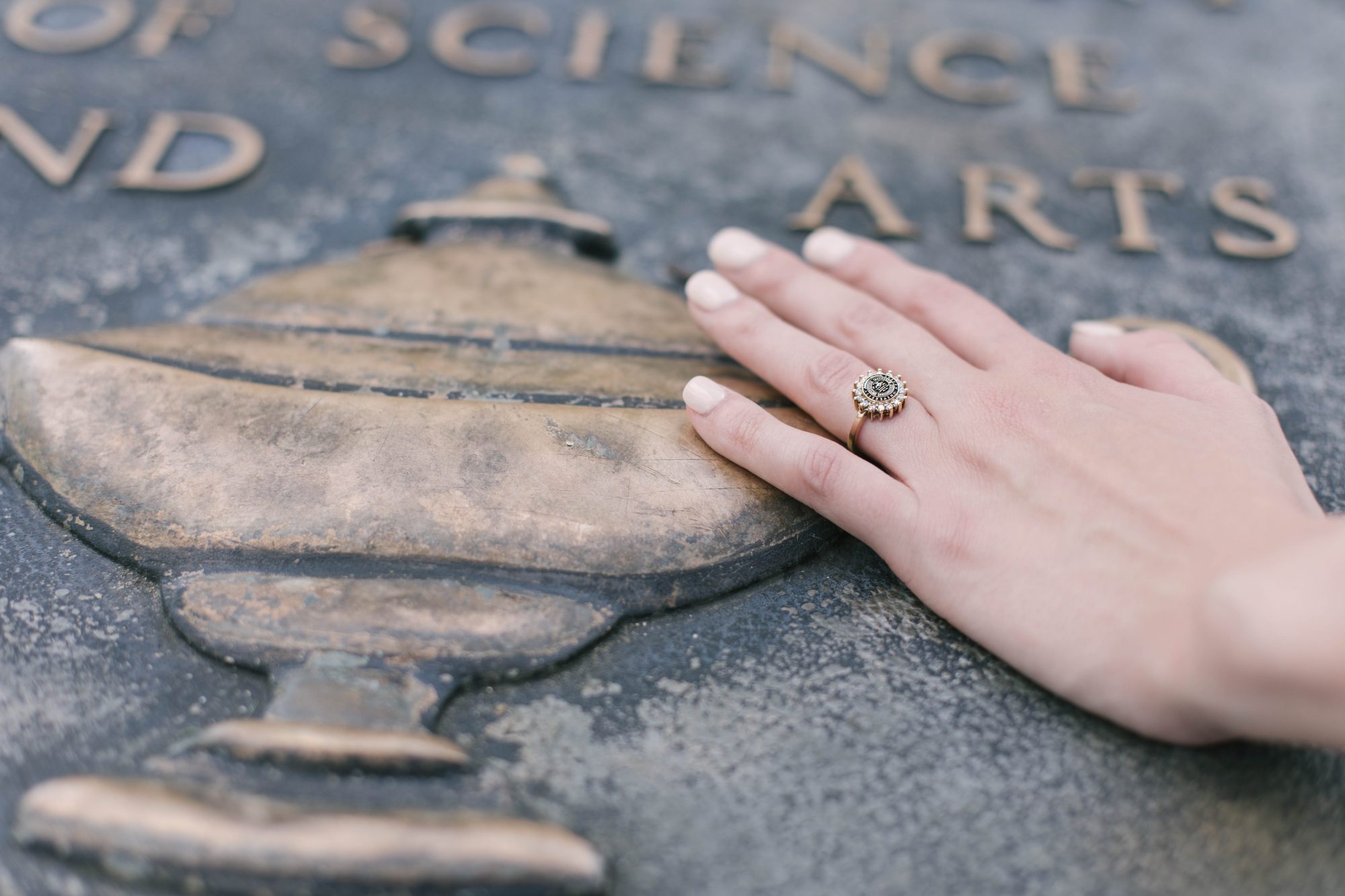 A hand wearing the Women's Dinner Ring places its hand over the Auburn Seal.